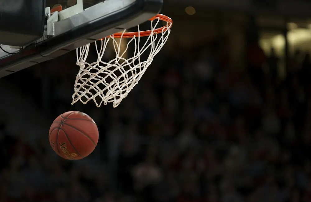 Balón de baloncesto bajo el aro de una canasta. Fotografía ilustrativa.